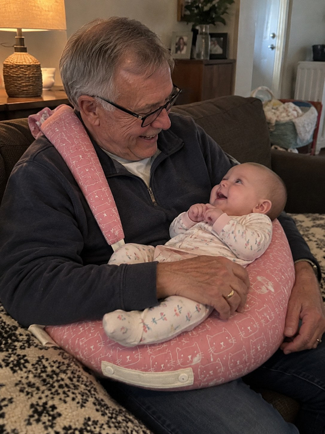 Grandpa holds the baby on the wearable pillow